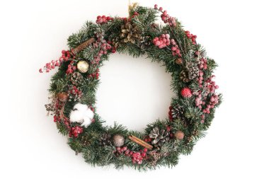 Beyaz duvarda asılı Noel çelengi. Geleneksel Noel çelengi kırmızı böğürtlen ve süslemeli, çam kozalağı ve beyaz üzerine izole edilmiş tarçın, bayram dekoru. Metin için boşluk