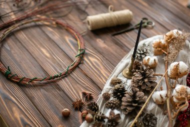 Kırsal Noel çelengi yapmak için dekorasyon. Dekoratif çam kozalakları, kırmızı böğürtlen, otlar, sicim, pamuk ve makas ahşap arka planda. Tatil atölyesi