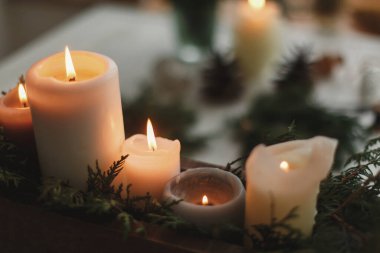 Kırsal arka planda mum yakmak, Noel çelengi, çam kozalağı ve akşam masa süsleri. Tatil atölyesi açılışı, sıcak atmosfer. Boşluğu kopyala