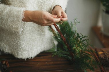 Kırsal Noel çelengi yapmak, tatil gelişimi. Kırsal ahşap arka planda yeşil sedir dalları tutan eller. Mevsimlik tatil atölyesi ya da evde şenlik dekorasyonu