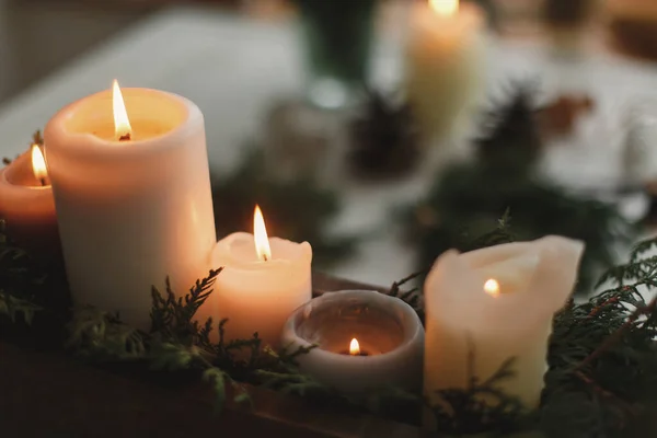 傍晚时分 在乡村的背景上用圣诞花环 松果和木制桌子上的装饰品燃点蜡烛 假日车间的到来 舒适的气氛 复制空间 — 图库照片