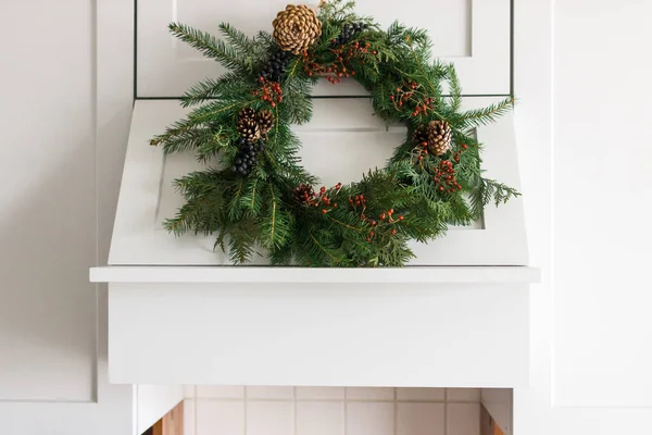 スタイリッシュなキッチンキャビネットにかかって創造的な現代のクリスマスリース モダンなキッチンフード お祝いの休日の装飾にぶら下がっている素朴なクリスマスリース メリークリスマスとハッピーホリデー — ストック写真