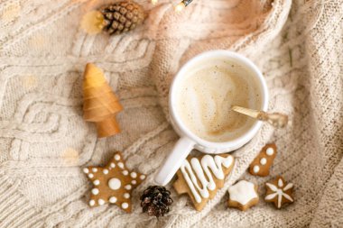Sıcak kahve arka planda örülmüş kazak, zencefilli kurabiye, çam kozalağı, ışık. Atmosferik kış ikilisi. İyi tatiller.