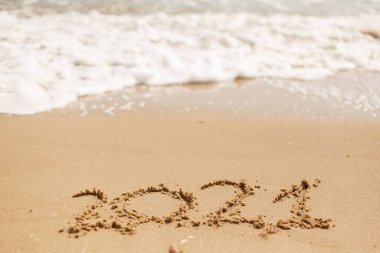 2021 'de kumlu sahilde el yazısı ve beyaz köpüklü. Mutlu yıllar 2021! 2021 'i yeni kararlarla, hayallerle, listelerle karşılıyoruz