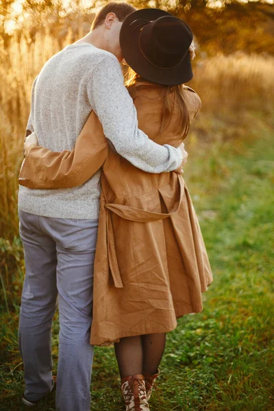 若いファッショナブルな女性と男性が秋のフィールドで採用 暖かい日没の光の中で秋の牧草地でキスを幸せなスタイリッシュなカップル ロマンチックな官能的な瞬間 — ストック写真