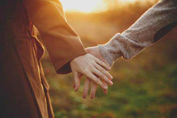 秋の牧草地で暖かい日没の光の中で静かに手を握って官能的なカップル 太陽の下で手を握っている若い男と女のクローズアップ ロマンチックな一緒に瞬間 概念的なイメージ — ストック写真