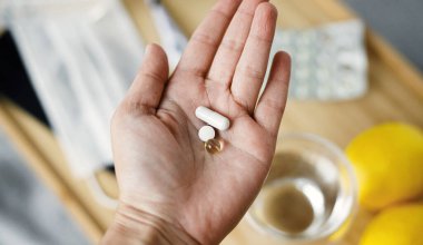 Grip ya da koronavirüs mevsiminde bağışıklık sistemini destekliyor. D vitamini, C vitamini ve çinko vitamini arka planda yüz maskesi, dezenfektan, termometre ve limonlu ahşap masa.