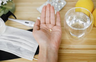 Ahşap masanın arka planında D vitamini, yüz maskesi, dezenfektan, termometre ve limon. Bağışıklık sistemini desteklemek, koronavirüs tedavisi. Sağlıklı kalın