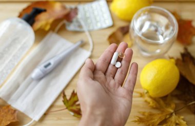 Sonbahar gribi mevsiminde veya koronavirüste bağışıklık sistemini güçlendirir. D vitamini, C vitamini ve çinko hapları arka plandaki ahşap masanın üzerine düşmüş yapraklar, yüz maskesi, dezenfektan, limon..