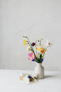 Mutlu kadınlar günü ve anneler günü. Kırsal beyaz masa üzerinde kurdele ve bahar çiçekleri olan şık bir hediye kutusu. Güzel nergisler ve laleler. Nazik buket ve hediye. Metin için boşluk