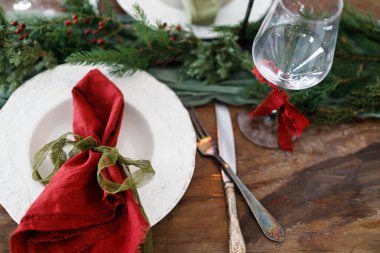 Modern tabaklar, kırmızı ve yeşil peçeteler, çatal bıçak, cam, köknar dalları, kırmızı böğürtlen, ahşap masada mum. Mutlu Noeller ve mutlu tatiller!