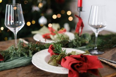 Modern tabaklar, kırmızı ve yeşil peçeteler, çatal bıçak, cam, köknar dalları, kırmızı böğürtlen, ahşap masada mum. Mutlu Noeller ve mutlu tatiller!