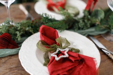 Modern tabaklar, kırmızı ve yeşil peçeteler, çatal bıçak, köknar dalları, kırmızı böğürtlenler, ahşap masadaki yıldız. Mutlu Noeller ve mutlu tatiller!