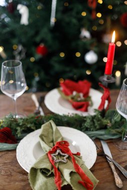 Modern tabaklar, kırmızı ve yeşil peçeteler, çatal bıçak, cam, köknar dalları, kırmızı böğürtlen, ahşap masada mum. Mutlu Noeller ve mutlu tatiller!