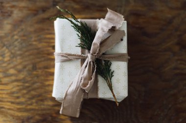 Noel hediyesi yatıyordu. Sedir dalı ve kırsal masada keten kurdeleyle sarılı şık bir Noel hediyesi. Mesaj için yer var. Çevre dostu tatiller. Sıfır atık
