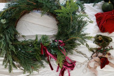 Mutlu Noeller ve mutlu tatiller! Kırmızı kurdeleli Noel çelengi, süsler ve kırsal masa üzerinde ekolojik hediye.