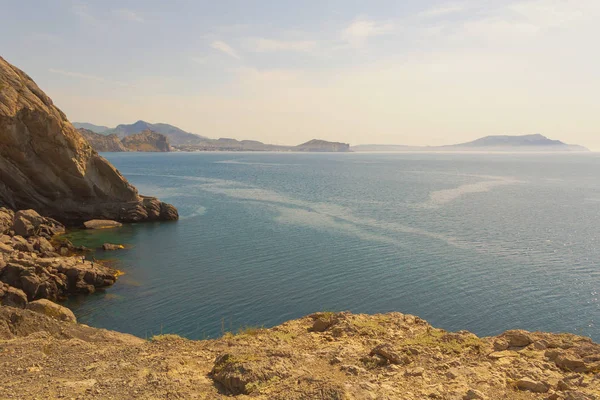 Yüksek uçurumdan denize parlak güneş ve dağ ufukta altında görüntüleyin. Crimea.