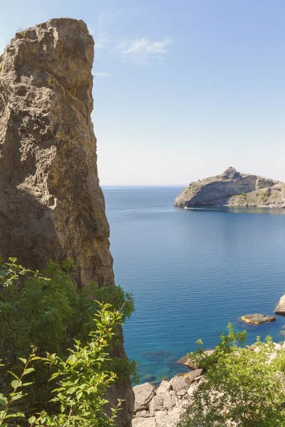 Yüksek rock ön planda, arkasında görünür deniz Bay, kıyı ve Cape uzaktan taş gibi.