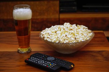 Bir bardak bira kase patlamış mısır uzak denetleyicileri ve ahşap arka plan ev yapımı eğlence gözlük