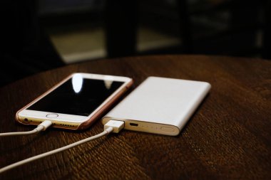 Powerbank akıllı telefonu ahşap arka planda şarj ederek görünümü kapatın