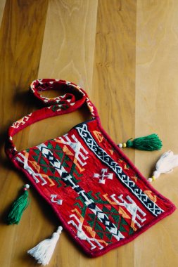 Ahşap arka plan yakından görünümü üzerinde etnik desenli kırmızı saddlebag çuval