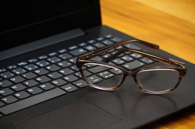 Ahşap arka planda gözlük ve bilgisayar klavyesi yakın görünüm iş konsepti