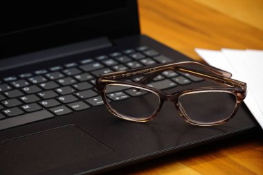 Gözlük dizüstü bilgisayar klavyesi ve ahşap arka plan iş konsepti üzerine notlar yakından görünümü