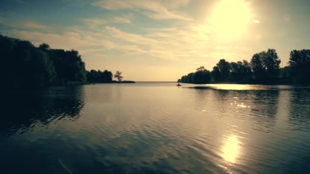 En medio de un río ancho un pescador coge un barco. El sol brillante brilla en el cielo azul . — Vídeo de stock