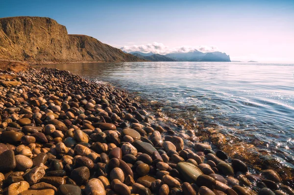 Stones at the shoreline which cover the beach of the Crimea shore on a Black sea.