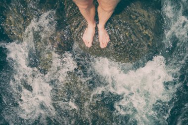 Bir taş bir temiz dağ nehir üzerinde çıplak ayakla ayakta adam. Seyahat kavramı.