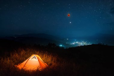 Camping tent in a mountain valley with total moon eclipse in a night starry sky. clipart