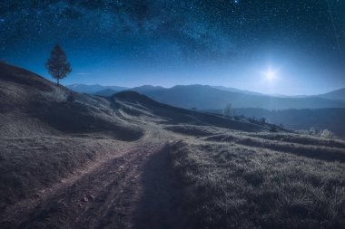 Yolda bir ışık tam ay yıldızlı gece gökyüzü altında dağ valley.