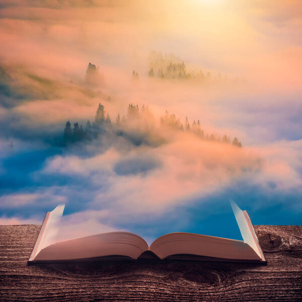 Majestic colorful sunrise in a misty valley on the pages of an open magical book. Majestic landscape. Nature and education concept.