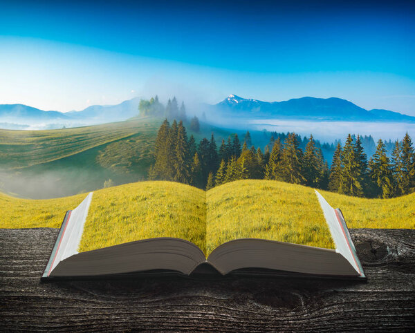 Carpathian mountain valley covered with morning fog on the pages of an open magical book. Majestic landscape. Travel and education concept.