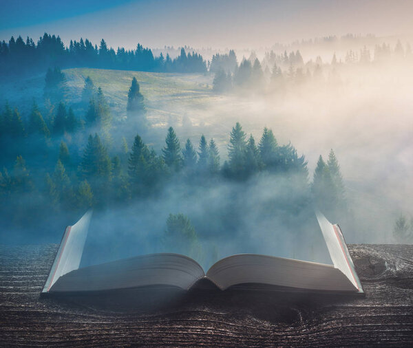 Beautiful sunrise in a Carpathian misty valley on the pages of an open magical book. Majestic landscape. Nature and education concept.