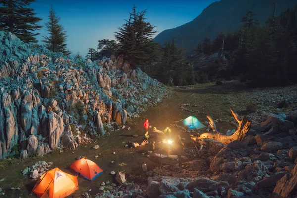 Group of hikers sitting near the campfire under the starry sky at night. Outdoor camping in a mountains of Turkey on a Lycian way.