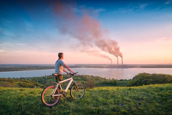 Homem com bicicleta olhando para a central elétrica — Fotografia de Stock