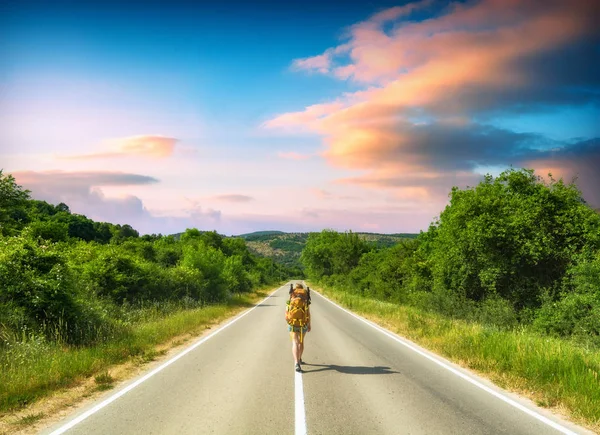 Wandermädchen mit Rucksack auf einer Bergstraße — Stockfoto