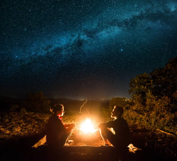Happy couple in silhouette near campfire