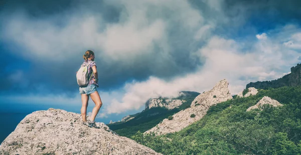 Wanderin auf einem Felsen genießt das sonnige Tal — Stockfoto