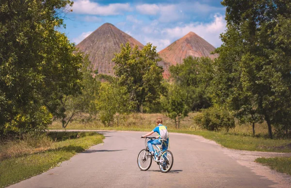 スラグヒープに対する道路上の自転車に乗った少年 — ストック写真