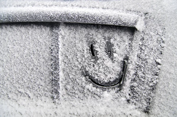 Smiling face  is drawn on  a snowy car window
