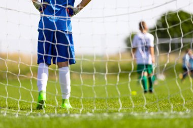 Futbol Eğitim oyun çocuklar için. Genç çocuk bir golü ayakta bir kaleci olarak. Sonra topu arka planda çalışan futbolcular. Okul açık spor yarışmaları