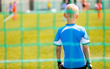 Futbol Eğitim oyun çocuklar için. Genç çocuk bir golü ayakta bir kaleci olarak. Sonra topu arka planda çalışan futbolcular. Okul açık spor yarışmaları