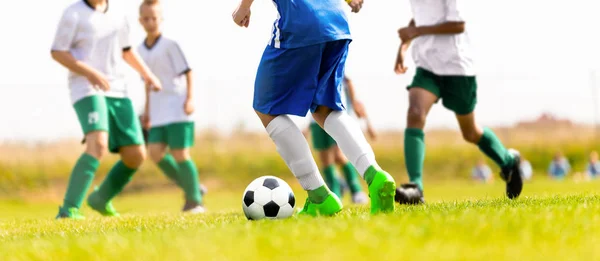 Young Boys Kicking Soccer Match on the Grass Pitch. Youth Sports Competition Between White and Blue Soccer Team