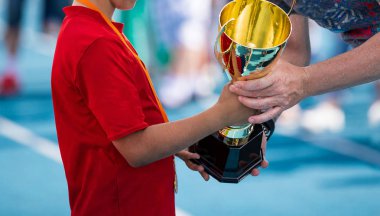 Altın kupa alma bir spor giyim çocuk. Genç atlete spor okulu yarışma kazanan. Çocuk ile altın madalya bir ödül turnuva oyuncu için en iyi Başlarken