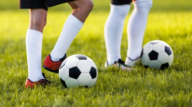 Bir çim sahada eğitim iki genç futbolcular. Bir spor giyim çocuklar. Beyaz futbol çorap ve futbol çizmeler giyen oyuncular. Futbol yatay arka plan
