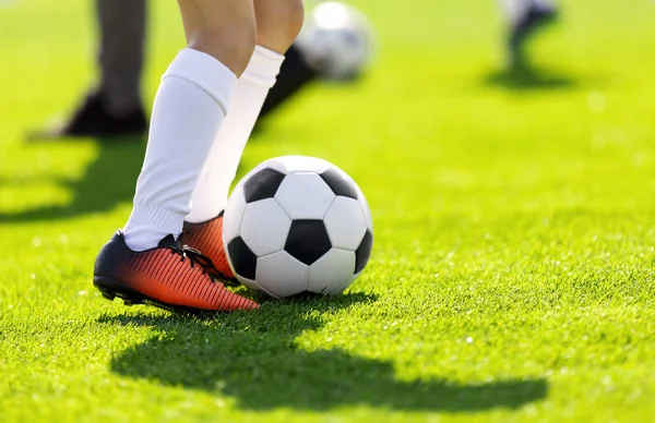 Bir futbol açık havada tekme bir genç adam. Genç futbolcuların çim sahada eğitim. Bir spor giyim çocuklar. Beyaz çorap ve futbol çizmeler giyen futbolcular. Futbol yatay arka plan