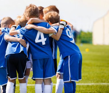 Erkek spor takımı koçu ile. Gençlik futbol takımının koçuyla toplanın. Motivasyon konuşmak, maçtan önce moral konuşması. Genç futbol futbol oyuncular jersey mavi spor giyim