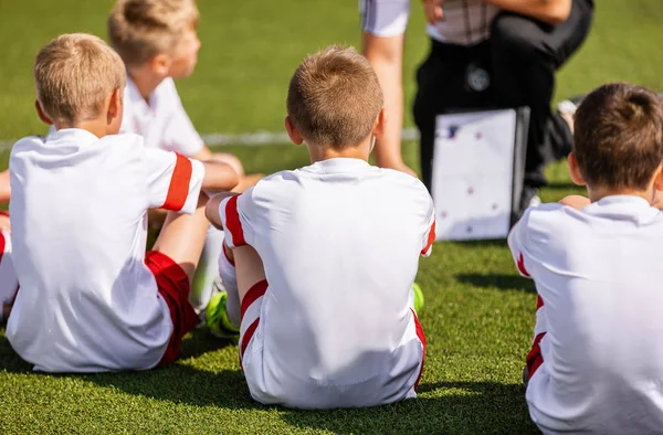 足球教练指导孩子们使用策略策略白板 足球教练向儿童足球队讲解比赛策略 男孩在运动衫看教练板 — 图库照片
